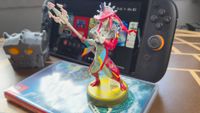 Photo by Rosalie Newcombe of the Sidon Tears of the Kingdom amiibo sitting in front of a Switch 2 on a wooden table.