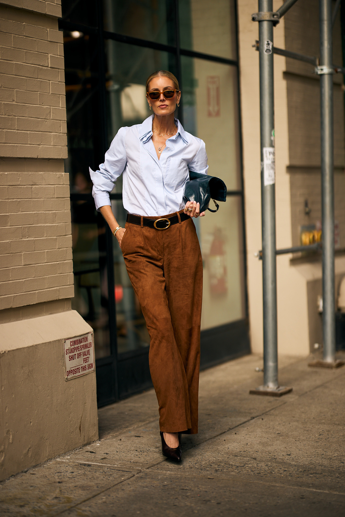 woman wearing button-down, suede pants, and heels