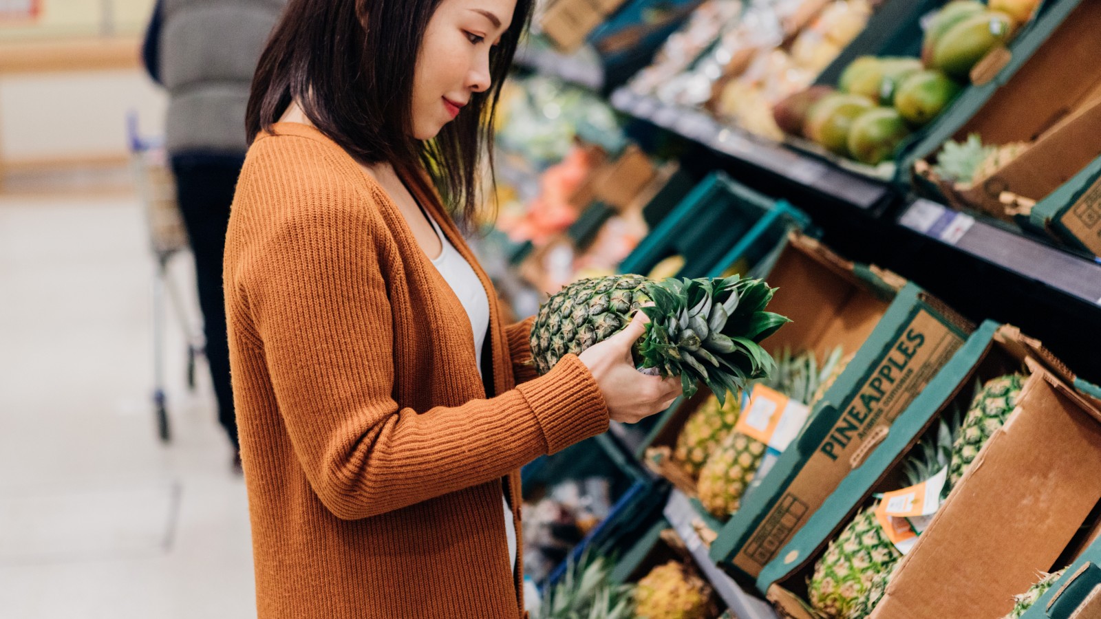Woman with pineapple in grocery store