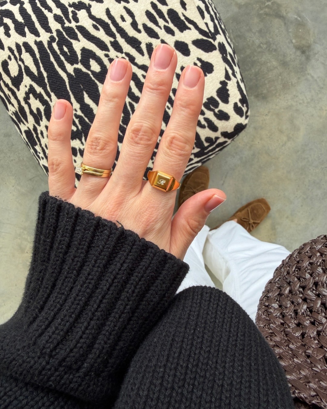 A woman taking a picture of her neutral manicure wearing gold rings