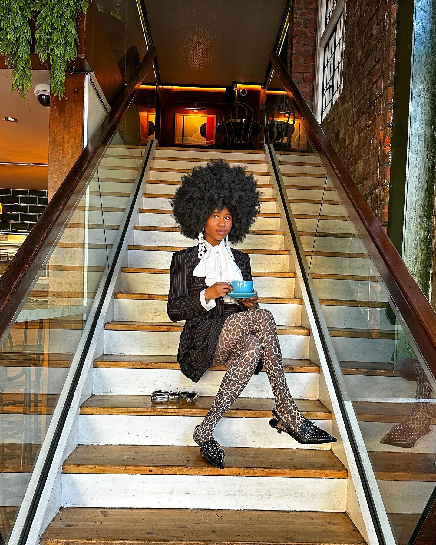 Blessing Afolayan sitting on a staircase with a teacup.