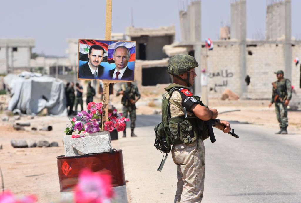 Members of Russian and Syrian forces stand guard near posters of Syrian President Bashar al-Assad and his Russian counterpart Vladimir Putin in Syria.