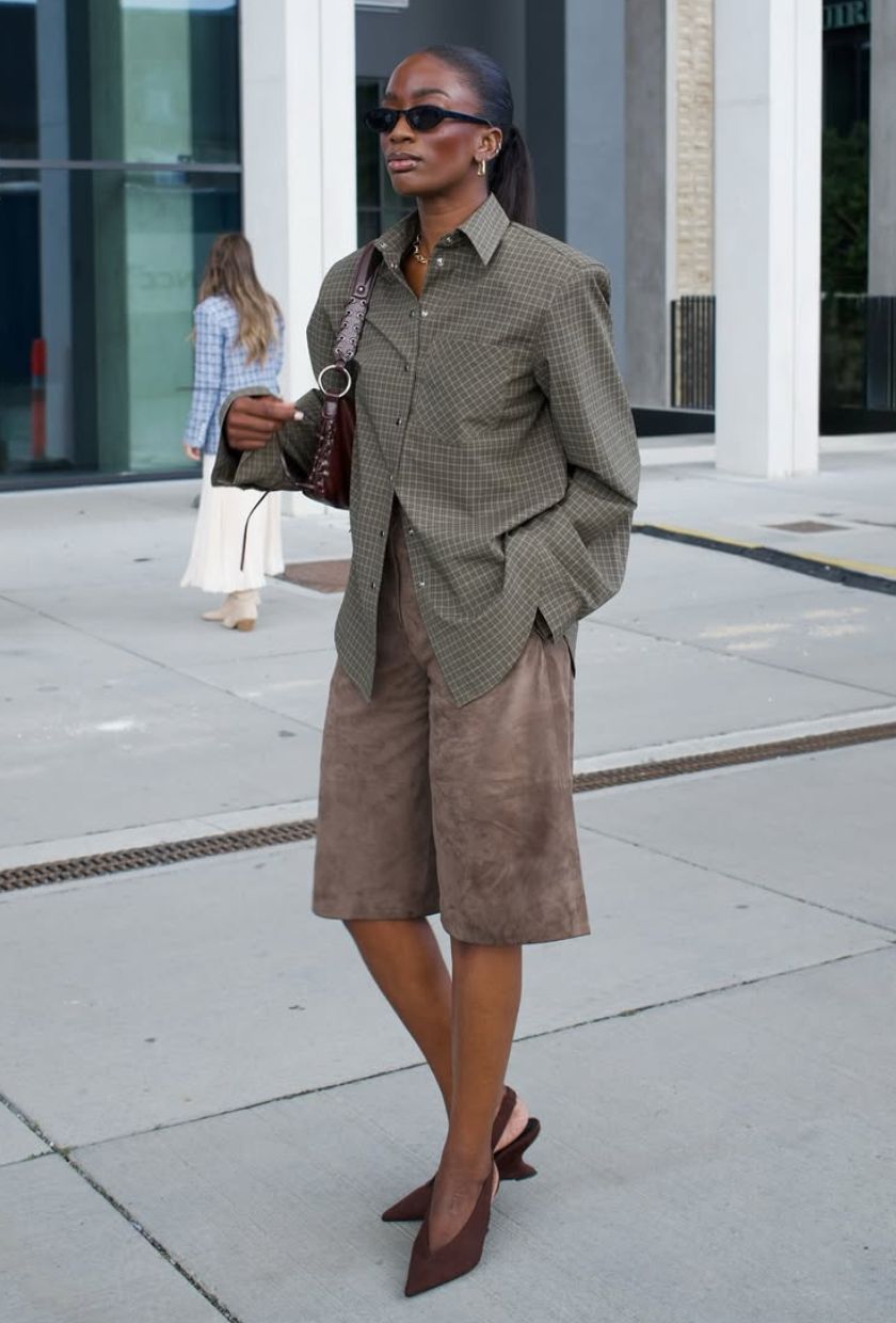@_livmadeline wears a khaki checked shirt, brown suede long shorts, burgundy wedge heels, a leather shoulder bag and sunglasses
