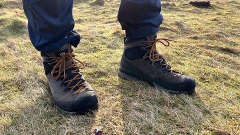 A pair of feet wearing Scarpa Mescalito TRK Pro GTX hiking boots, standing on grass