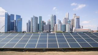 A row of solar panels sat in front of the skyline of Singapore