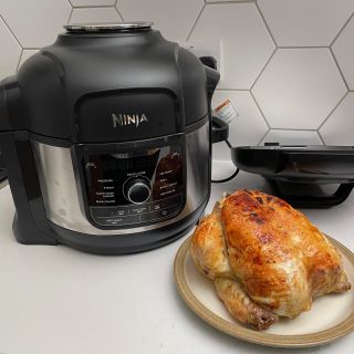 Ninja Foodi 9-in-1 Multi-Cooker with whole cooked chicken on a cream plate