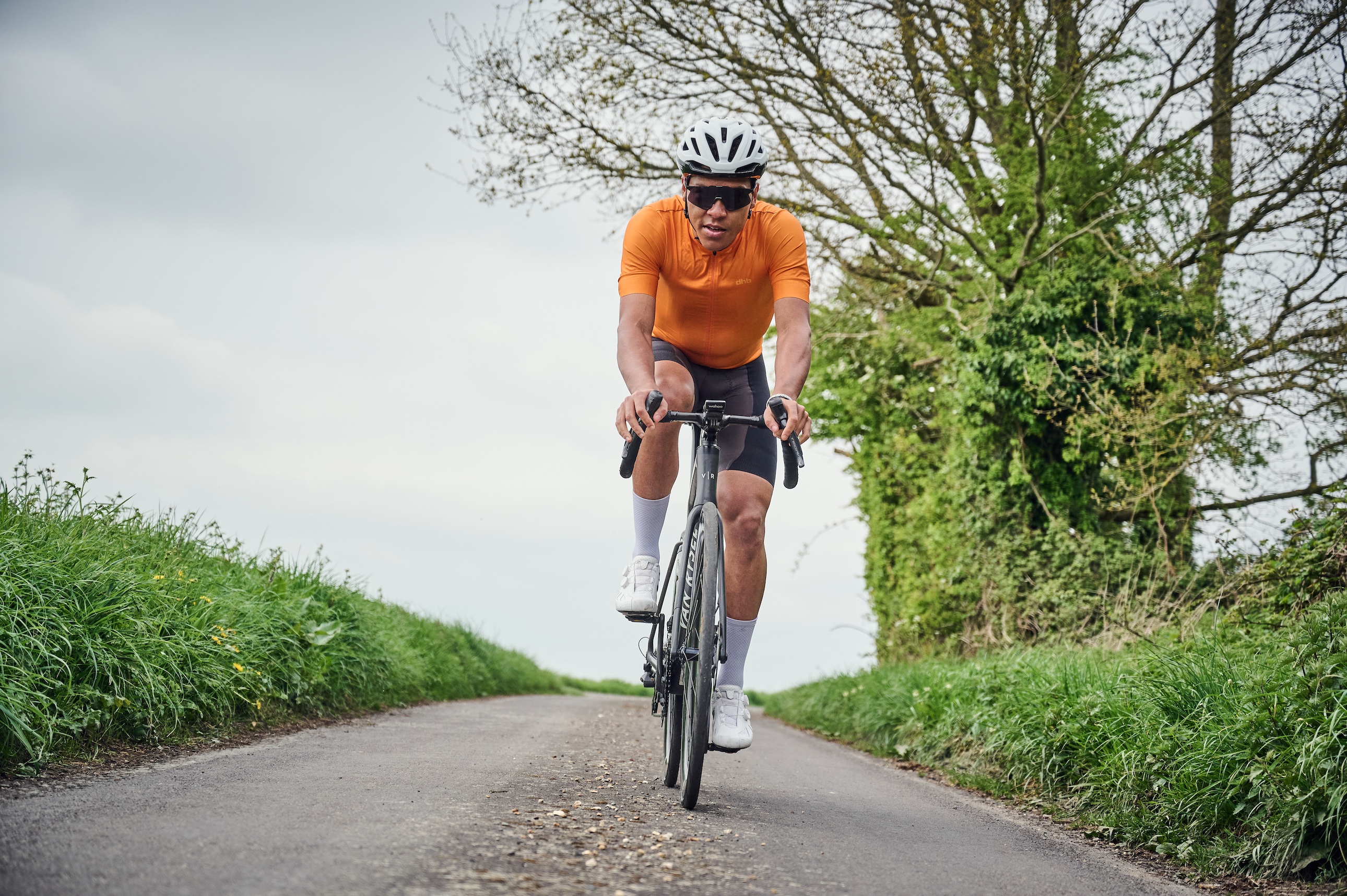 A rider in an orange jersey on a country road