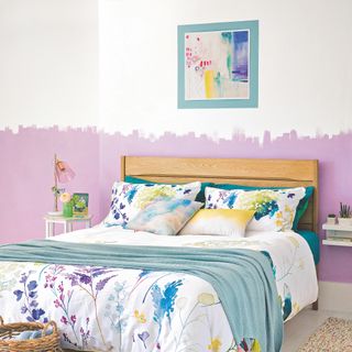 lilac painted bedroom with floral watercolour bedlinen and pale aqua throw