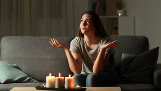 Someone sitting at home with nothing to do during a power outage, with candles on a table