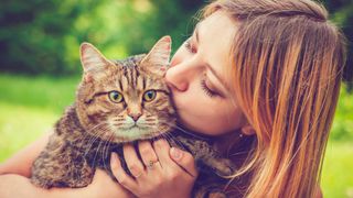 Young woman hugging her cat outside