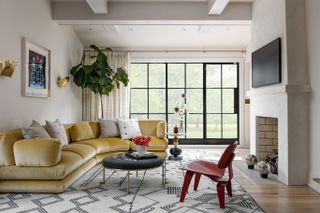 A living room with white walls and ceiling, white carpet and a yellow long couch