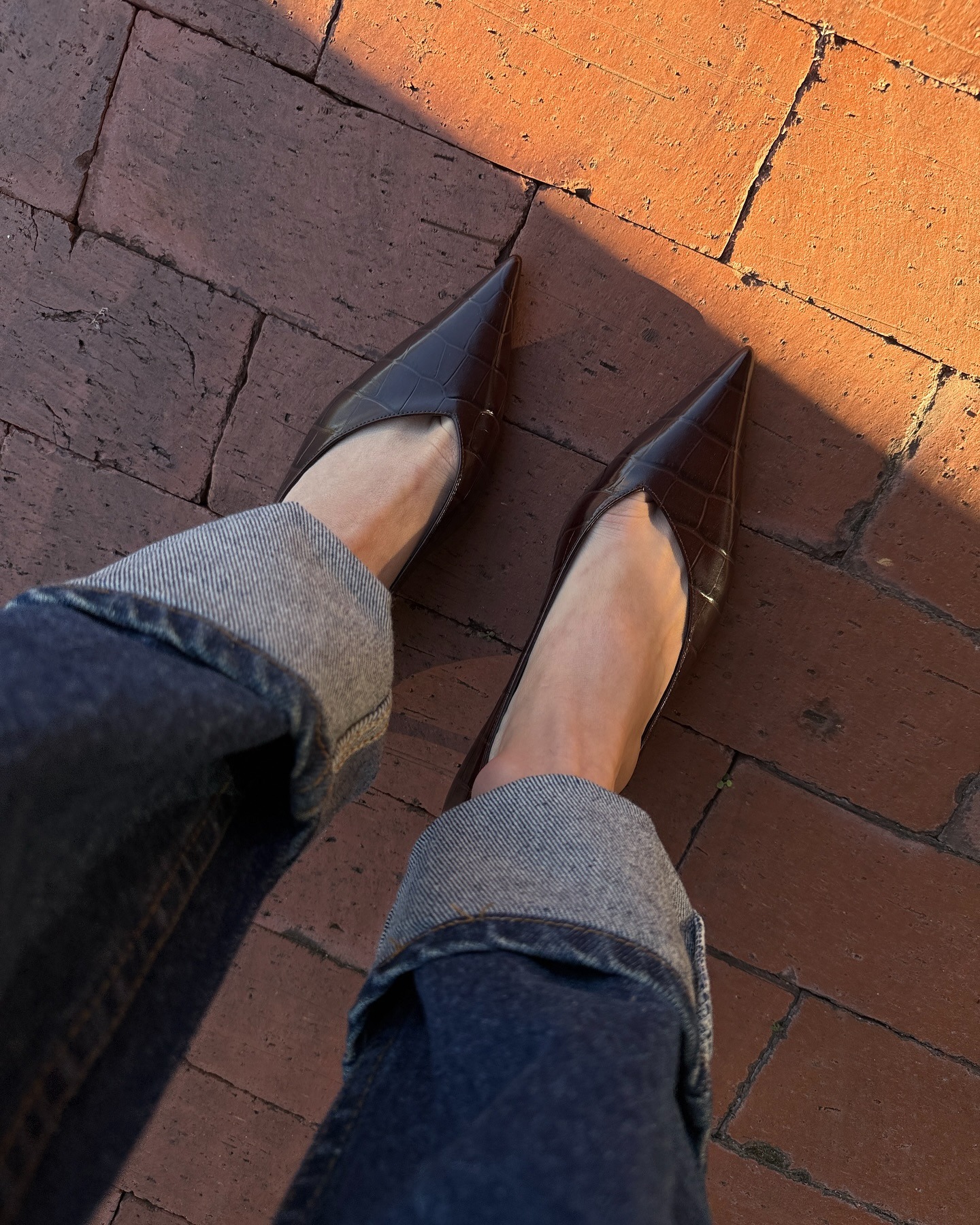 brown croc heels with cuffed jeans on bricks