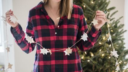 Caucasian woman holding Christmas ornaments on string - stock photo