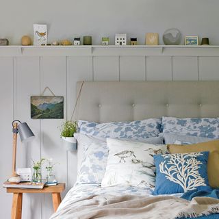 white wall bedroom with shelf above bed grey bed with designed cushion