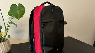 Timbuk2 Division backpack in red, white and black sitting on a black table next to a plant