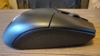 A black Corsair Katar Elite Wireless gaming mouse on a brown wooden table