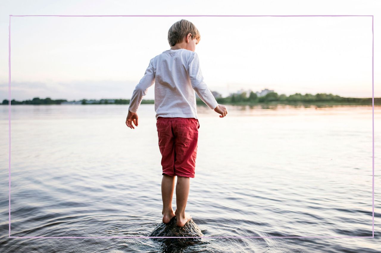 Child stood on a rock in a lake