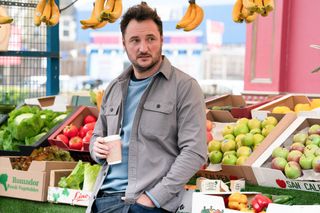 Martin Fowler drinking coffee and leaning against his fruit and veg stall.