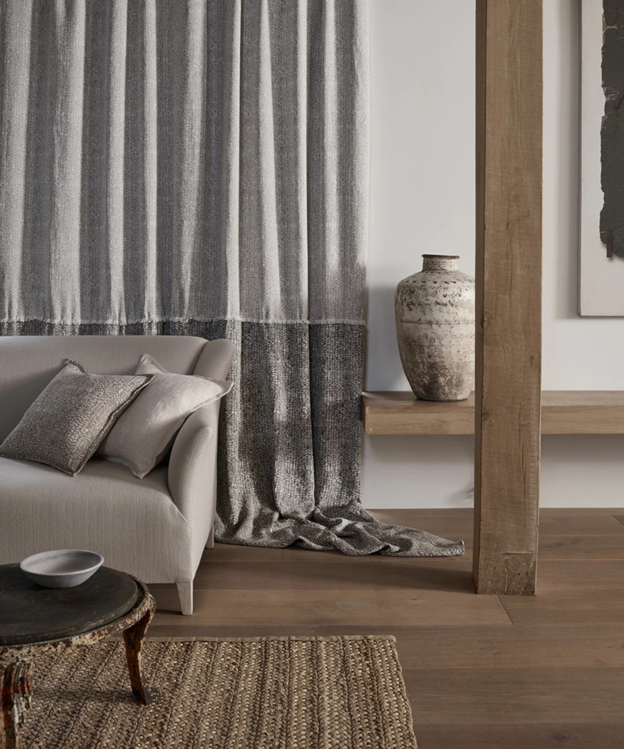 silver colored sofa with sustainable upholstery in front of grey two tone fabric and wooden floors