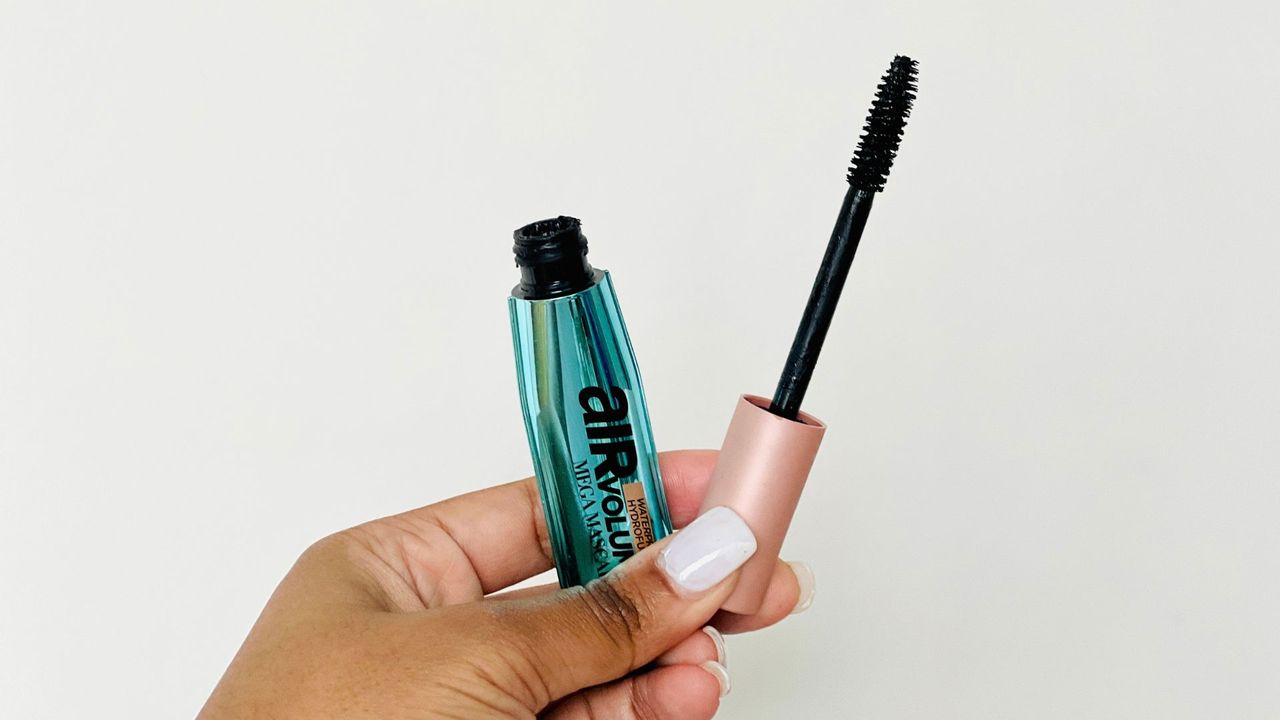 A person holding an opened metallic blue mascara tube for the best L'Oreal mascara.