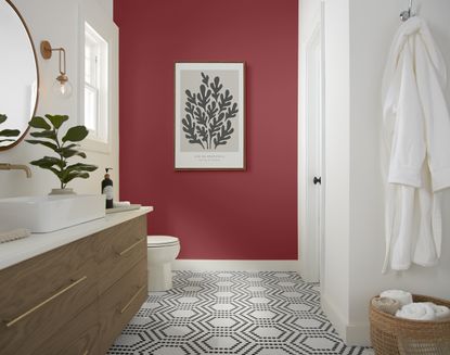 A bathroom with a red accent wall, tiled flooring, and a black vanity 