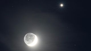 a bright crescent moon under a pale yellow orb