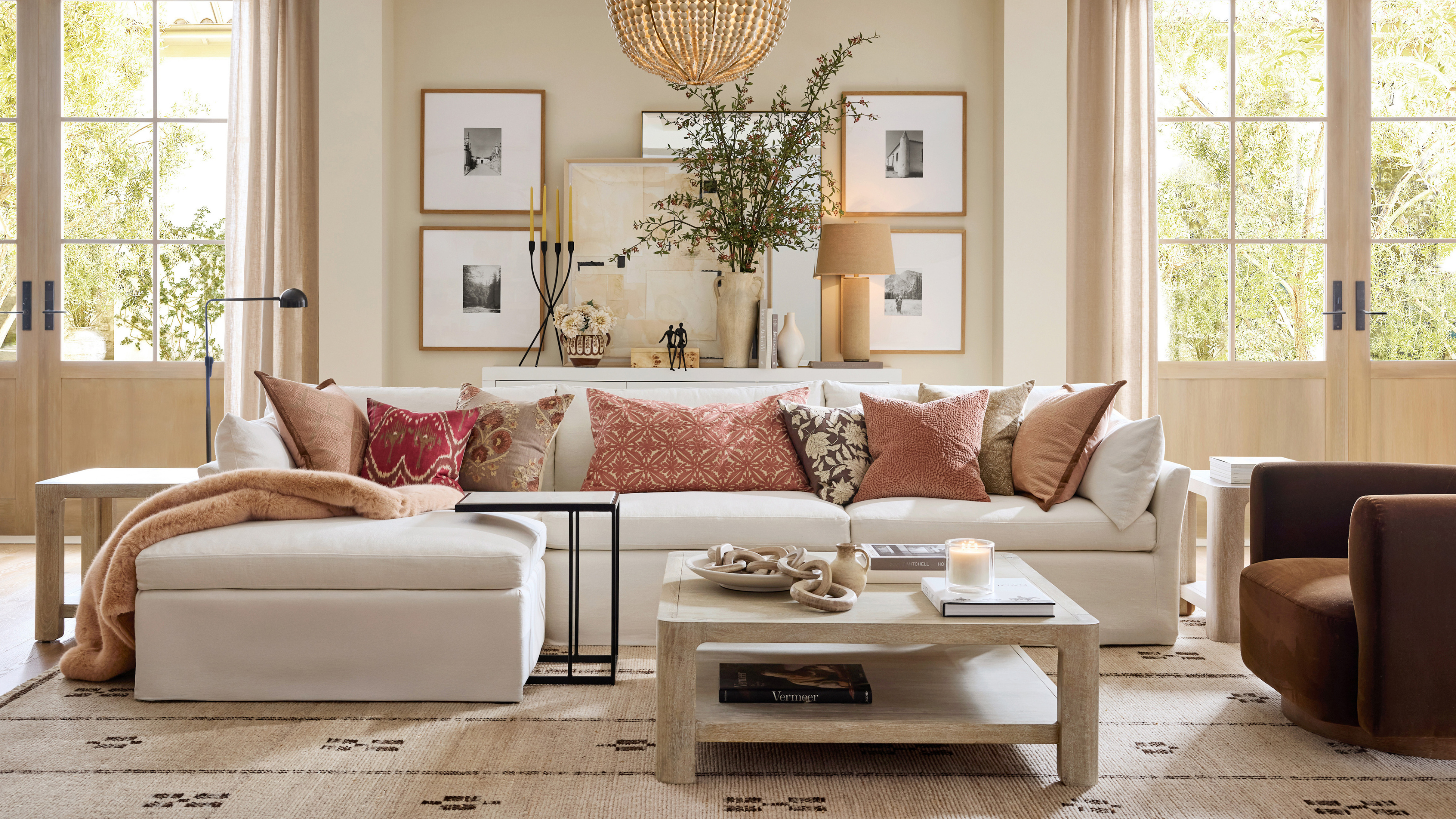 Large grey orner sofa with coral cushions in a neatral, contemporary living room.