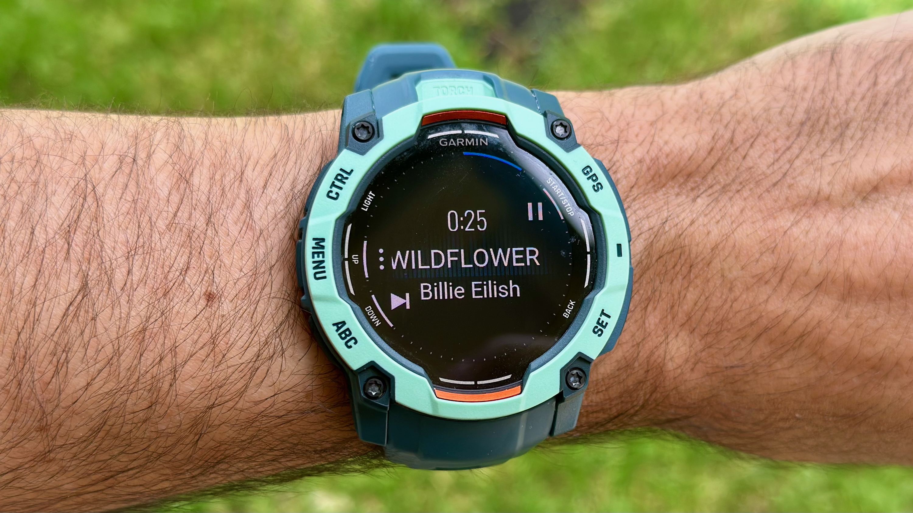 The Garmin Instinct 3 50mm AMOLED showing the music playback controls with 