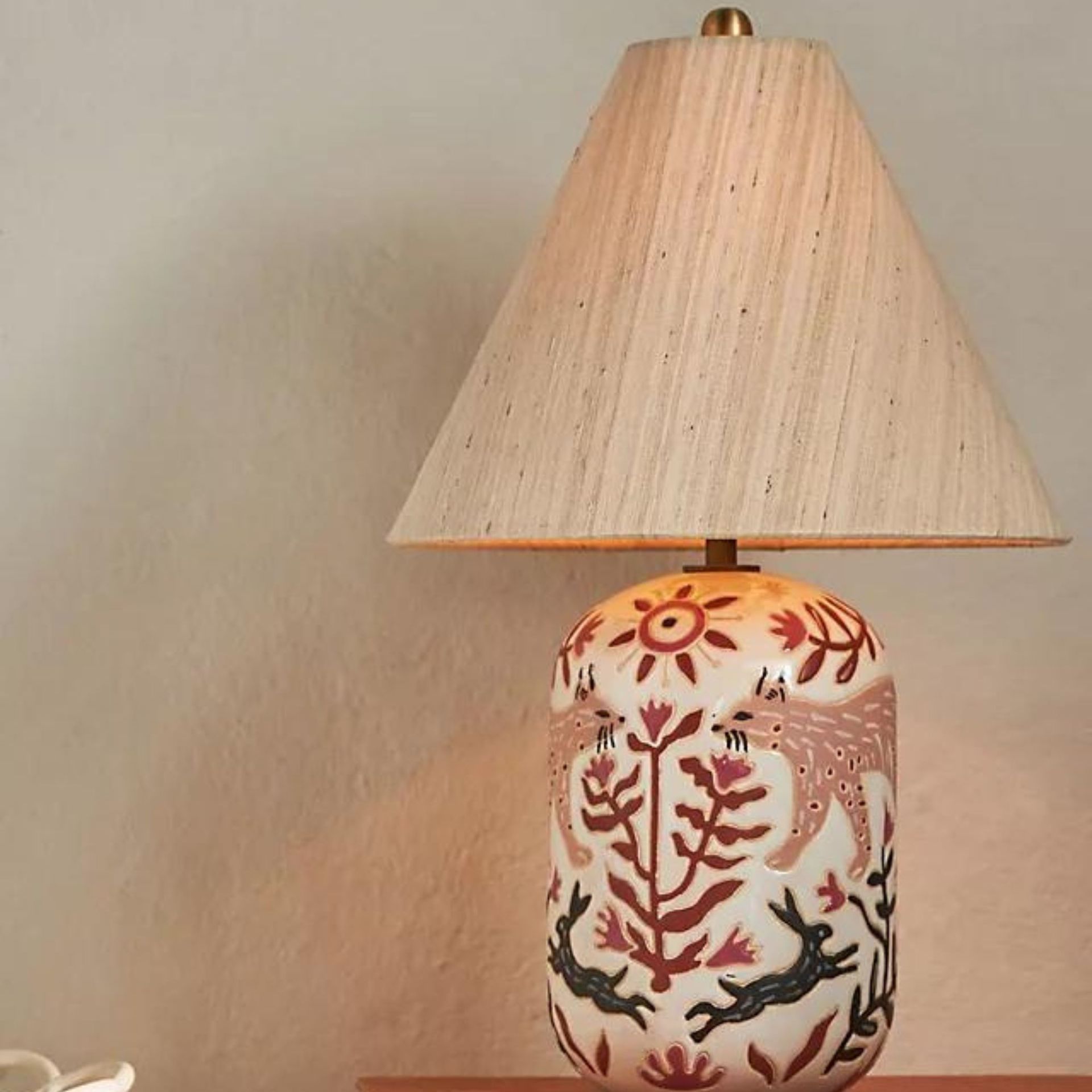 A tan lampshade on a painted table lamp