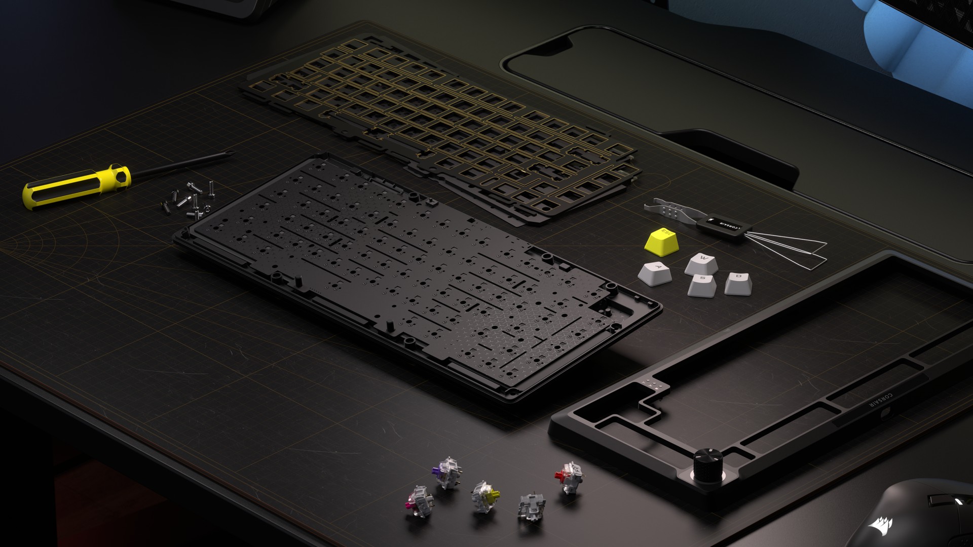 Corsair MAKR 75 barebones kit on a black mouse pad with switches and keycaps surrounding it
