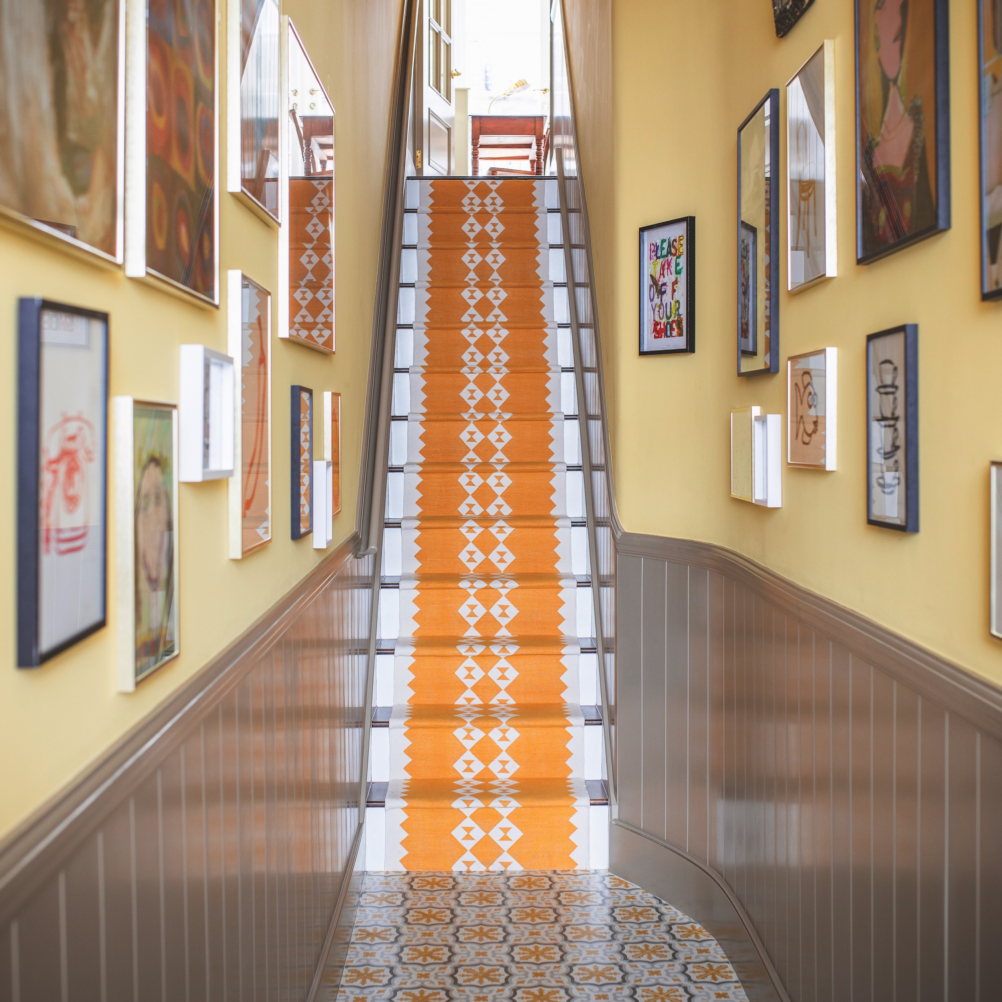 narrow hallway with brown wood panelling and stairs with yellow runner