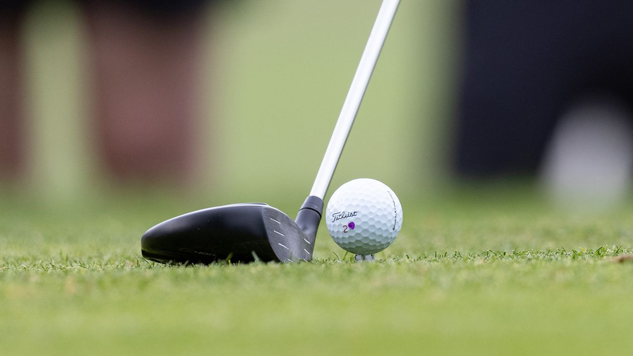 A golfer lining up to hit a 3-wood off the tee