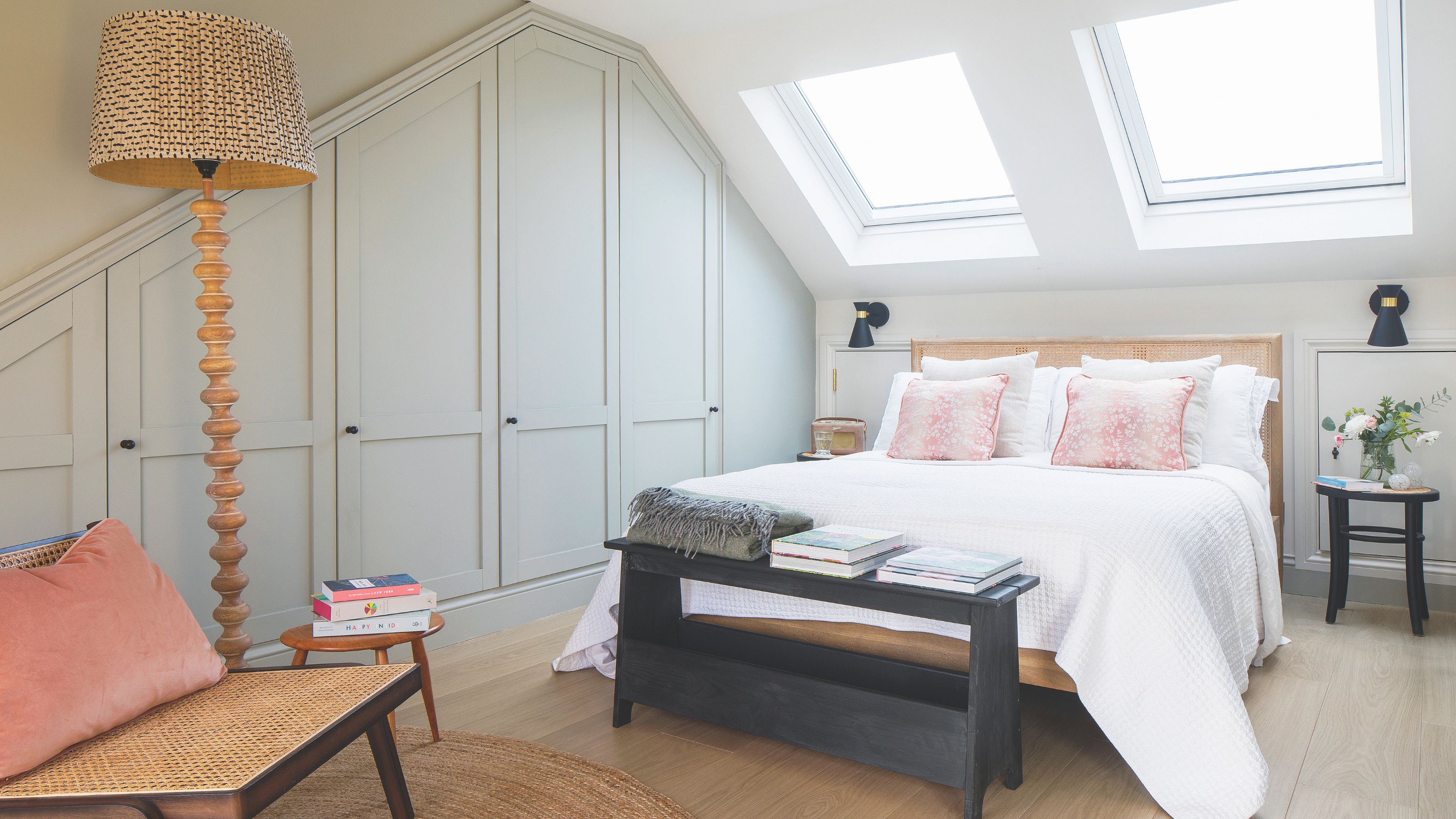 Loft bedroom with grey fitted wardrobes and a big bed underneath two windows