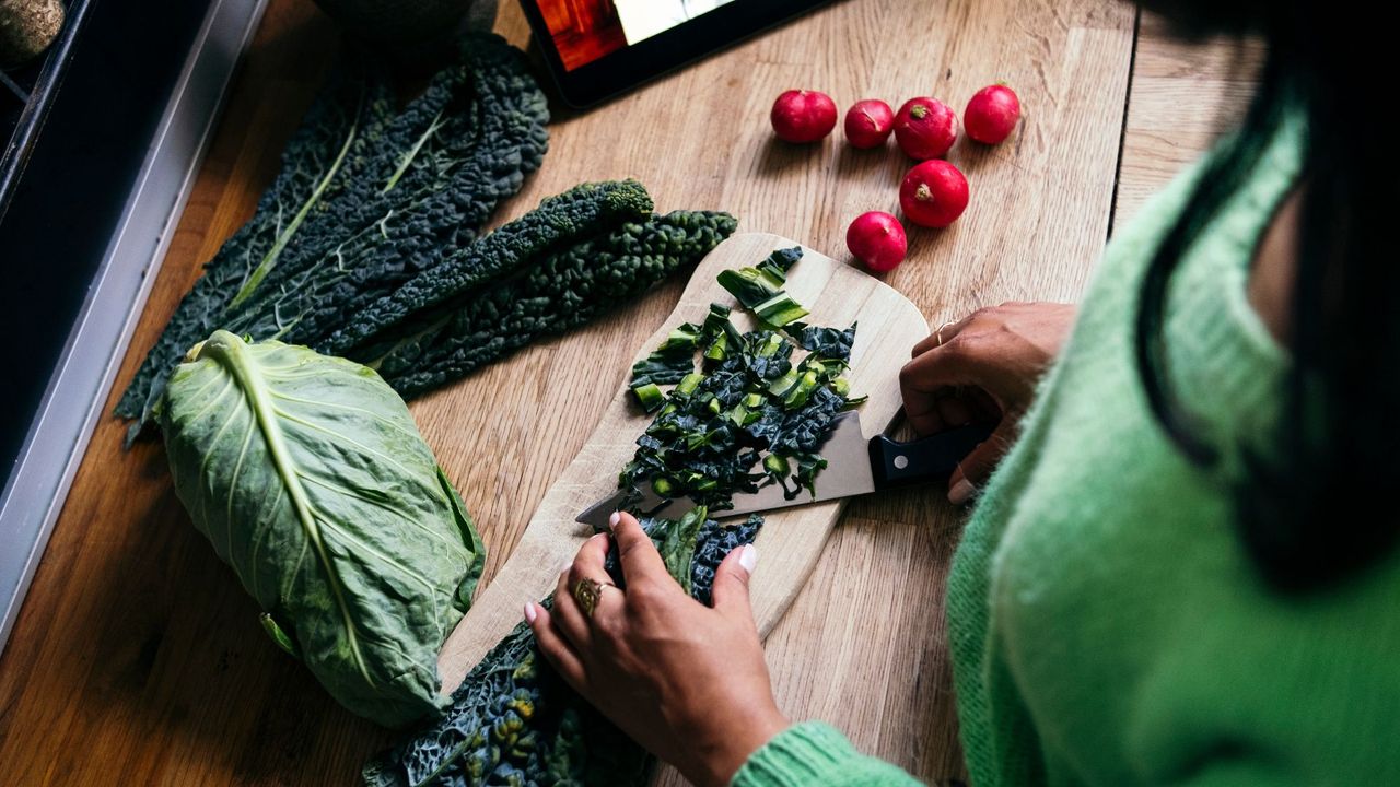 Best foods to eat for hormones: A woman chopping kale