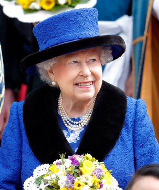 The queen in blue and black suit and hat