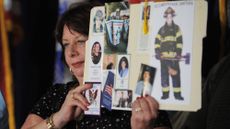 Maureen Santora holds up photos of NYC firefighters killed on 9/11 (including her son) before a pre-trial session for Khalid Sheikh Mohammed in 2008 at Guantanamo Bay. 