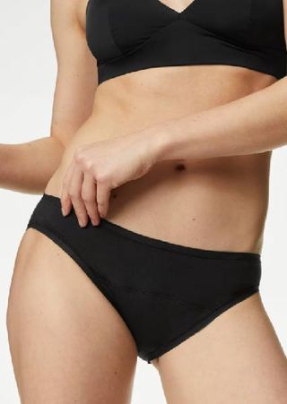 A close up of a model wearing a black bikini from M&S