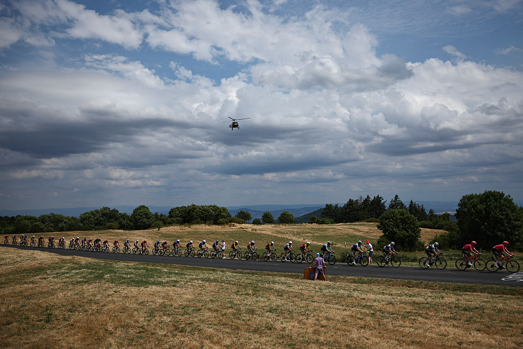 The pack of riders (peloton) cycles in the ascent of the Cote de Berzet during the 10th stage of the 112th edition of the Tour de France cycling race, 165.3 km between Ennezat and Le Mont-Dore Puy de Sancy, in central France, on July 14, 2025. (Photo by Anne-Christine POUJOULAT / AFP)