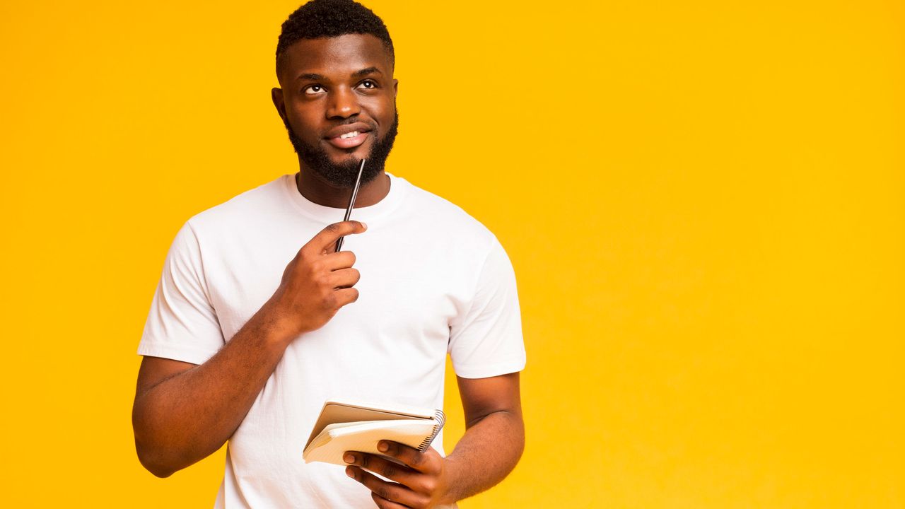 A man chews on a pencil as he looks over a checklist.