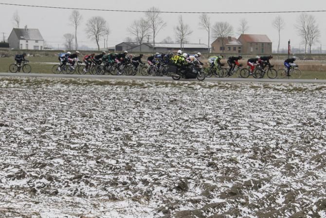 The peloton passes a snow-covered field at Gent-Wevelgem