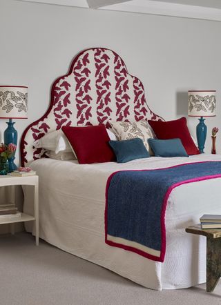 Guest bedroom idea with a punchy patterned headboard in a shapely silhouette, with blue and red scatter pillows.