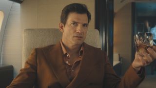 The Corporation (Byron Forster) holding glass of liquor in private jet in The Beauty Season 1