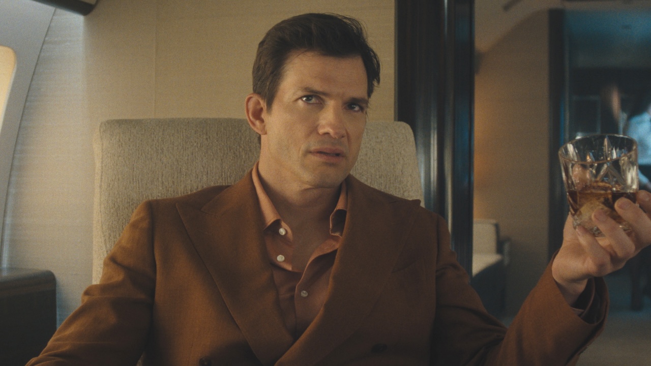 The Corporation (Byron Forster) holding glass of liquor in private jet in The Beauty Season 1