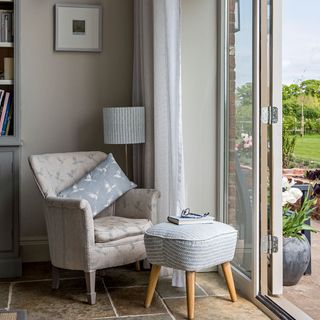 grey wall grey armchair with cushion near glass door