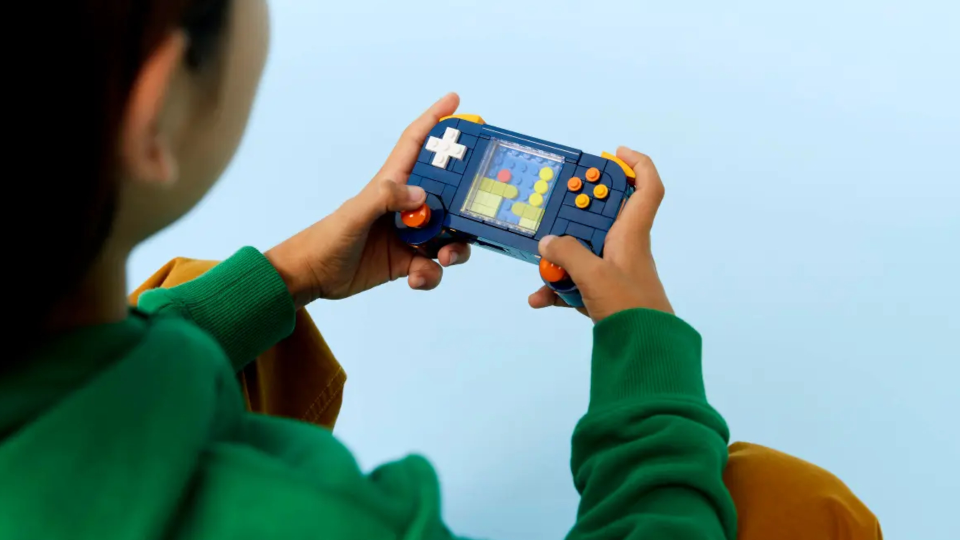 A child plays with a Lego retro console against a blue background