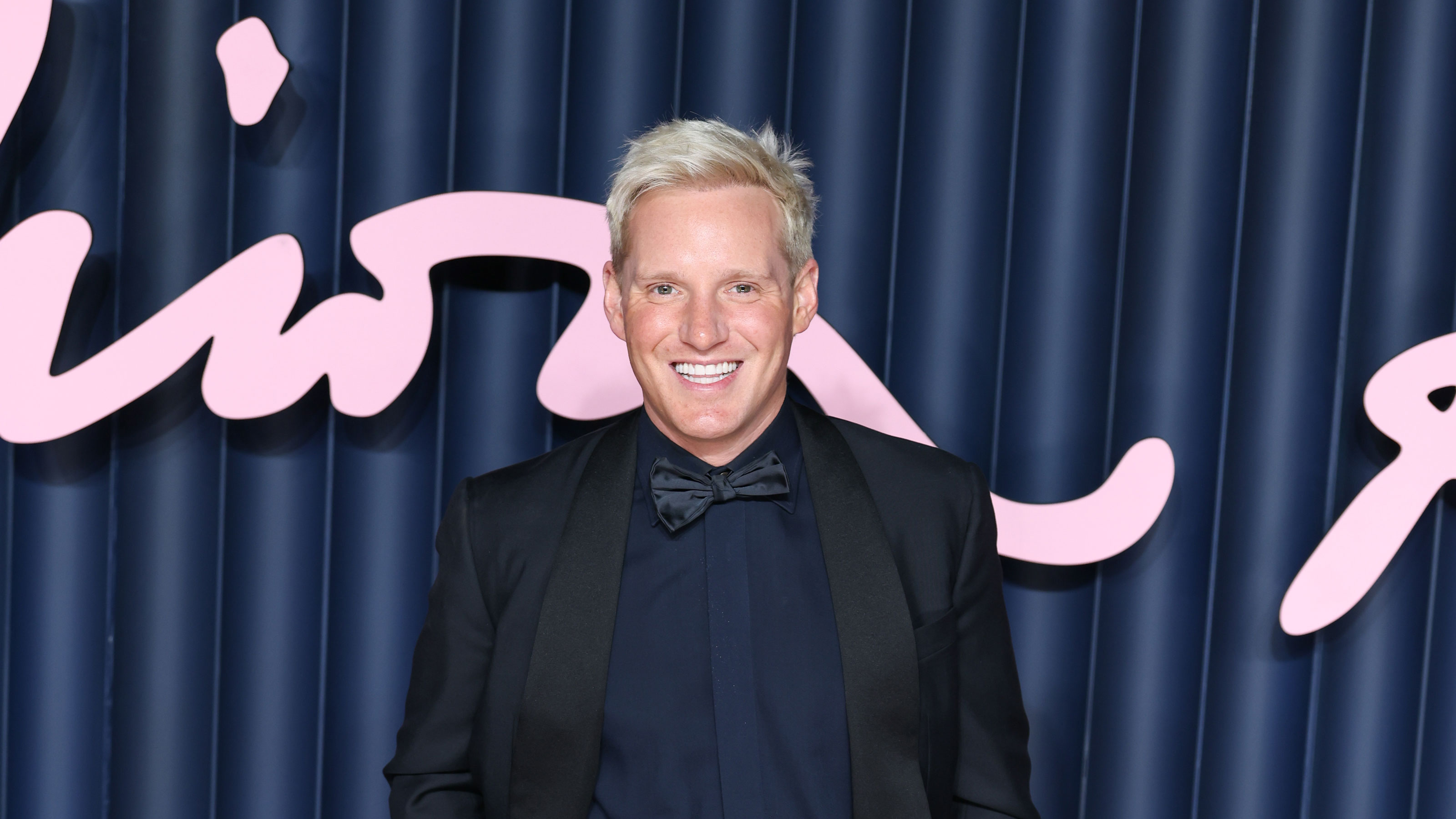 Jamie Laing in a blue suit in front of a blue background