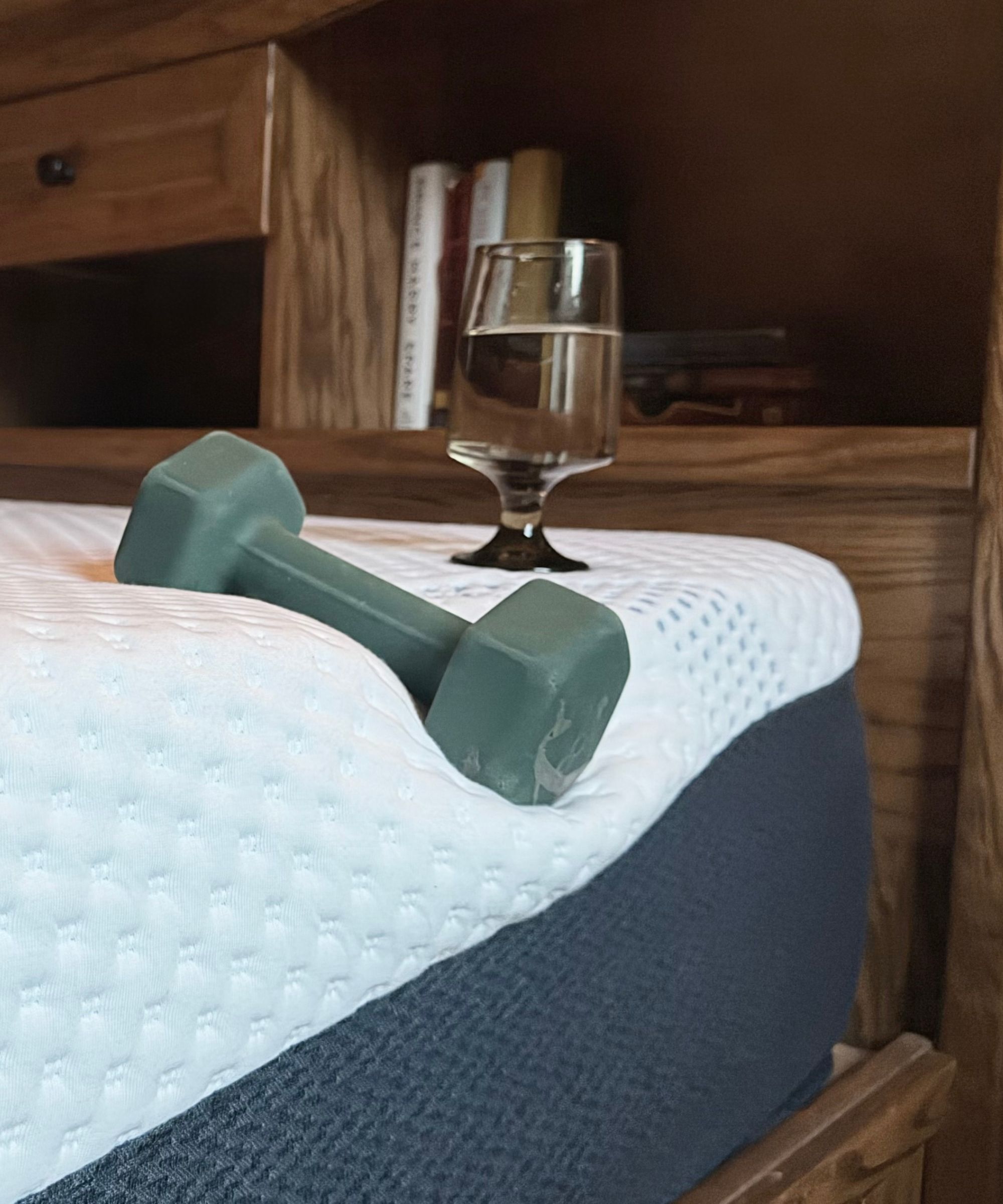 Testing the edge support of the Sleep Number ComfortNext mattress, with a wine glass filled with water and a green weight.