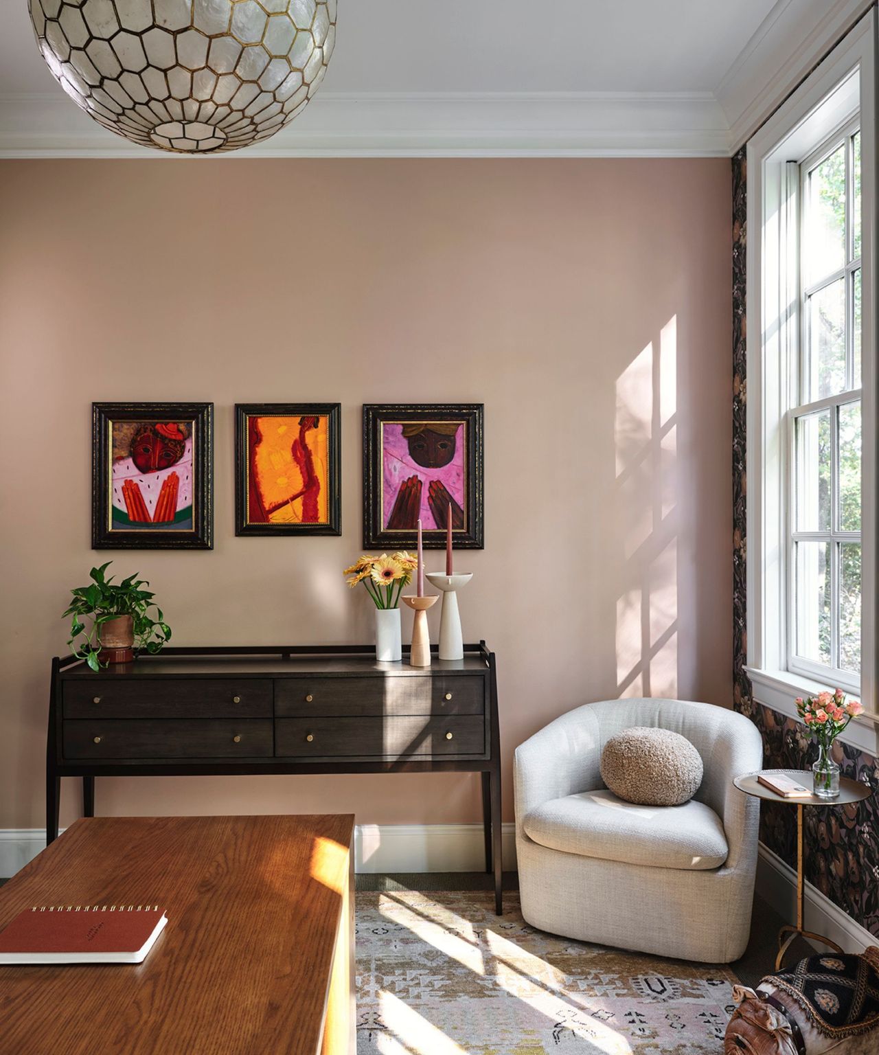 A pink sitting room with a console table and glass light fixture