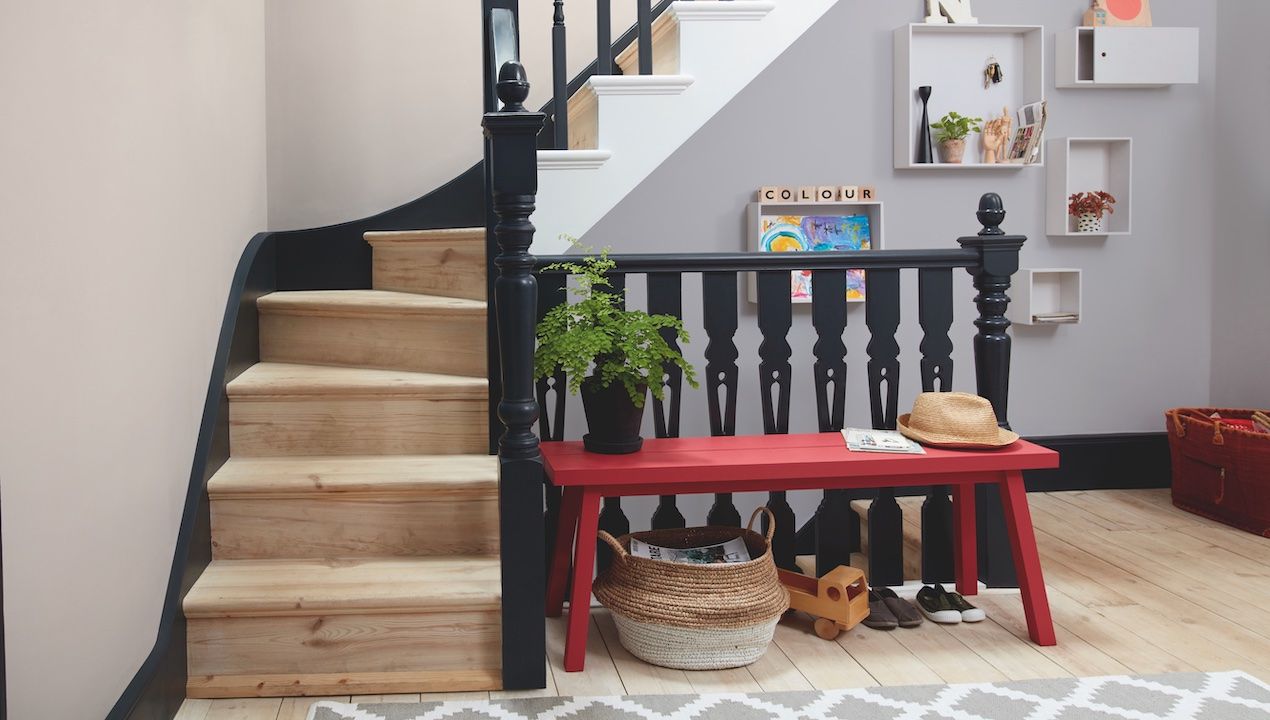 hallway with black banisters and red bench, wooden floors and sisal basket