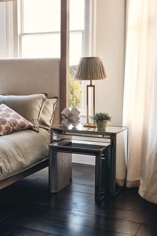 neutral bedroom scheme with upholstered headboard, dark wooden floor, Venetian glass side tables